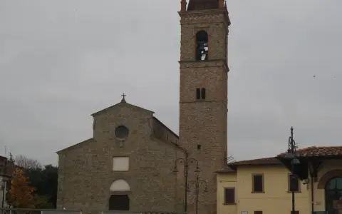 La chiesa di Sant'Agostino ad Arezzo, con il suo imponente campanile in pietra, si staglia contro un cielo nuvoloso.