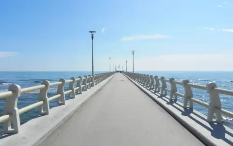 Il pontile di Forte dei Marmi si estende verso il mare azzurro sotto un cielo limpido, invitando a una passeggiata.