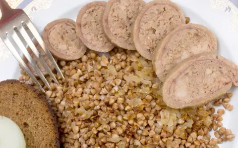 Piatto con grano saraceno, pane nero, cipolle e fette di collo ripieno.