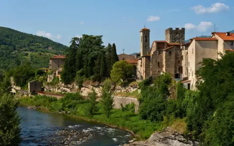 Borgo medievale di Subbiano, Arezzo, con il fiume che scorre ai suoi piedi e il verde rigoglioso che abbraccia le antiche pietre.