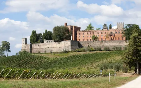 Il castello di Brolio domina le colline toscane, circondato da vigneti rigogliosi e cipressi secolari.