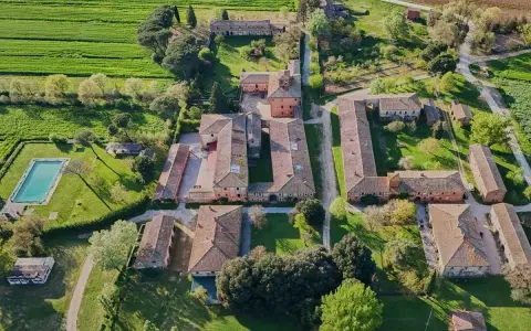 Un complesso rurale con piscina e campi verdi, tipico della campagna di Montagnano Arezzo.