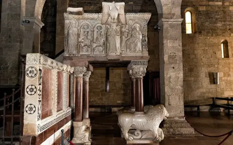 Interno del duomo di Barga con un leone in marmo e un pulpito scolpito.