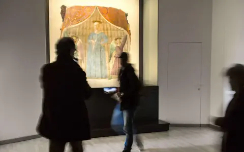Un'opera d'arte a Monterchi, cosa vedere: visitatori ammirano un affresco con figure sacre in un museo.