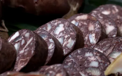 Fette di biroldo toscano, un salume scuro con striature bianche, pronto per essere gustato.