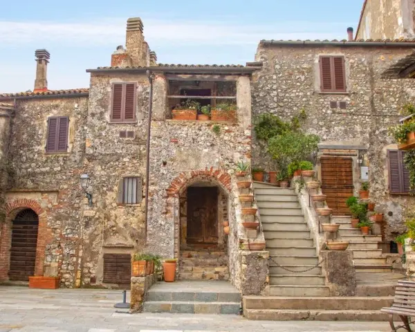 Antica piazza con case in pietra e scale fiorite, ideale per scoprire borghi da visitare in 2 giorni.