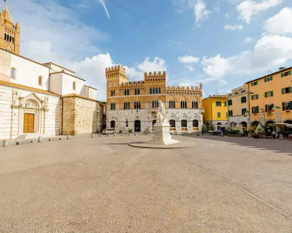 Piazza del Popolo a Grosseto, Italia, con il Duomo, il Palazzo Aldobrandeschi e case colorate.