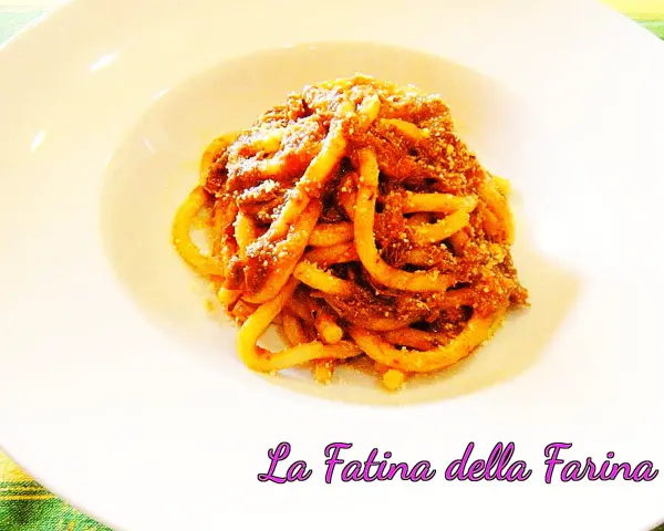 Pici alla nana, un piatto di pasta fatta in casa condita con un ricco ragù, servito su un piatto bianco.