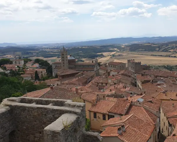 Panoramica di Massa Marittima con tetti rossi, una cattedrale imponente e colline toscane sullo sfondo.