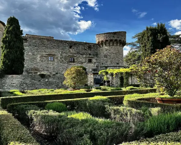 Giardini curati e torri antiche del castello di Meleto, un luogo ideale per visite indimenticabili.