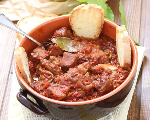 La scottiglia, un saporito stufato di carne in umido, servita in una ciotola di terracotta con fette di pane croccante.