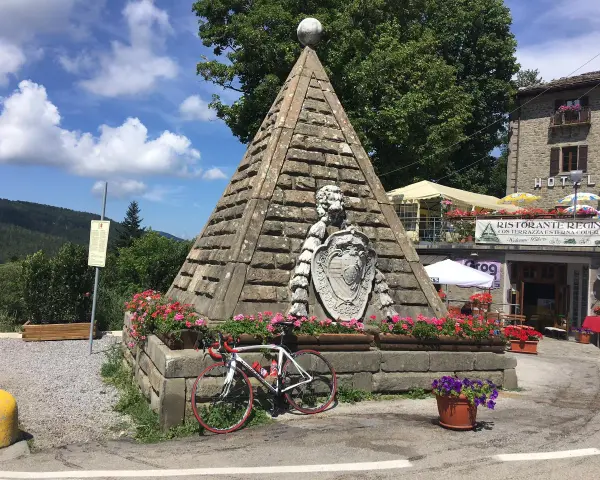 Le piramidi di Abetone, con una bici da corsa appoggiata, circondate da fiori e un ristorante.