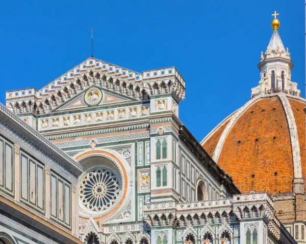 Dettagli architettonici del Duomo di Firenze, un must per chi visita Firenze cosa vedere. La cupola del Brunelleschi domina il cielo azzurro.