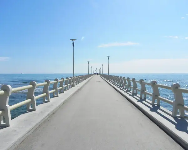Il pontile di Forte dei Marmi si estende verso il mare azzurro sotto un cielo limpido, invitando a una passeggiata.