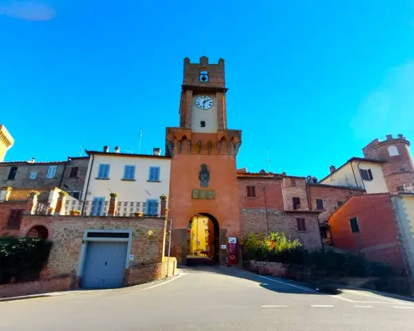 Torre dell'orologio a Marciano Italia, con un arco medievale e case in pietra.