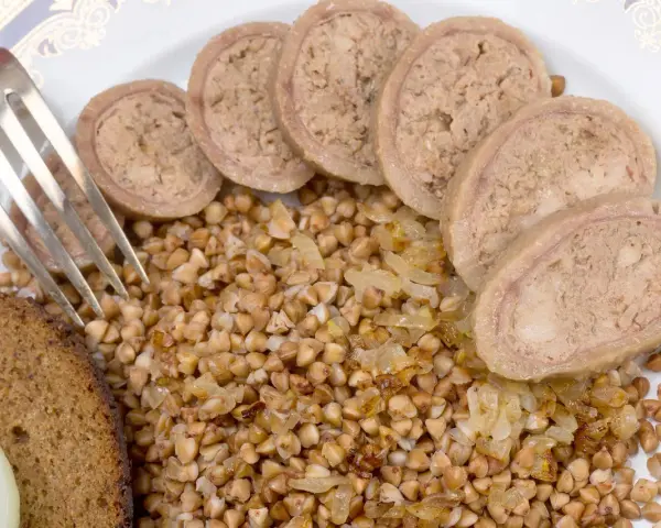 Piatto con grano saraceno, pane nero, cipolle e fette di collo ripieno.