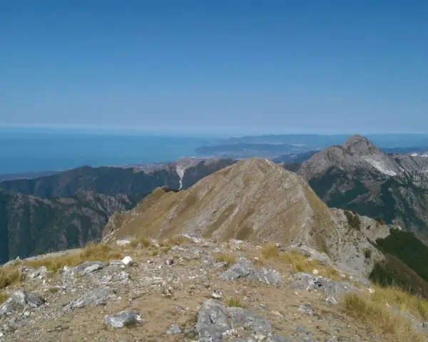 Panoramica mozzafiato dal monte Argegna, con il mare azzurro all'orizzonte e le cime rocciose che si stagliano contro il cielo limpido.