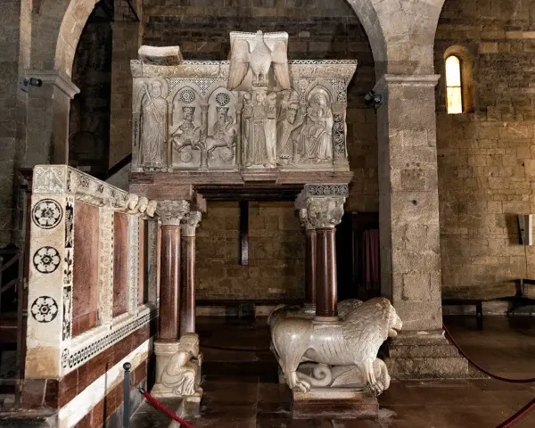 Interno del duomo di Barga con un leone in marmo e un pulpito scolpito.
