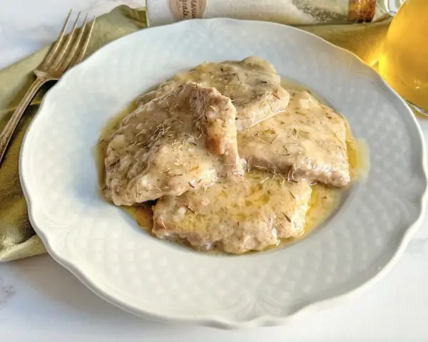 Grifi in umido, teneri e succulenti, serviti su un piatto bianco con forchetta e bicchiere di vino.