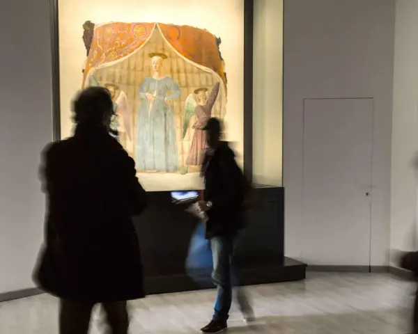 Un'opera d'arte a Monterchi, cosa vedere: visitatori ammirano un affresco con figure sacre in un museo.