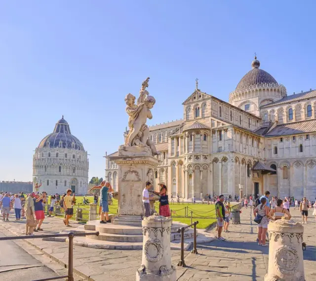 La piazza del Duomo a Pisa, con il Battistero, la Cattedrale e la celebre torre di Pisa, gremita di turisti.