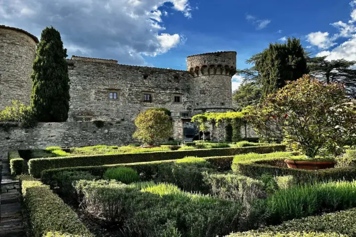 Giardini curati e torri antiche del castello di Meleto, un luogo ideale per visite indimenticabili.