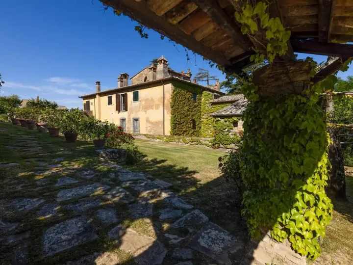 Un casale toscano immerso nel verde, con un pergolato ricoperto d'edera. Un luogo ideale per gustare un buon dionisio vino.