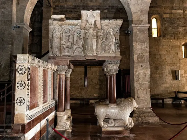 Interno del duomo di Barga con un leone in marmo e un pulpito scolpito.