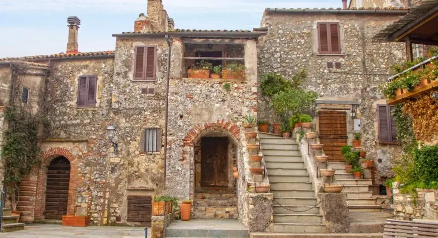Antica piazza con case in pietra e scale fiorite, ideale per scoprire borghi da visitare in 2 giorni.