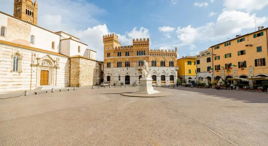 Piazza del Popolo a Grosseto, Italia, con il Duomo, il Palazzo Aldobrandeschi e case colorate.