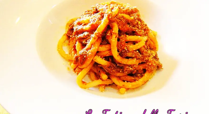 Pici alla nana, un piatto di pasta fatta in casa condita con un ricco ragù, servito su un piatto bianco.