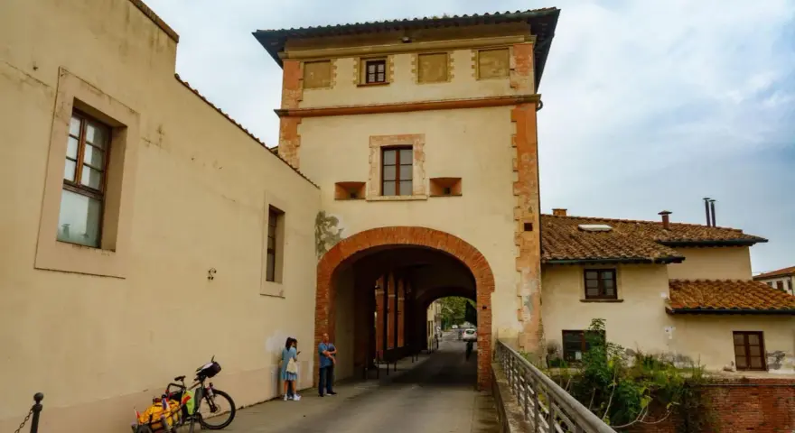 Un arco imponente a Santa Maria a Monte, con una coppia che osserva la strada. Una bici carica attende.