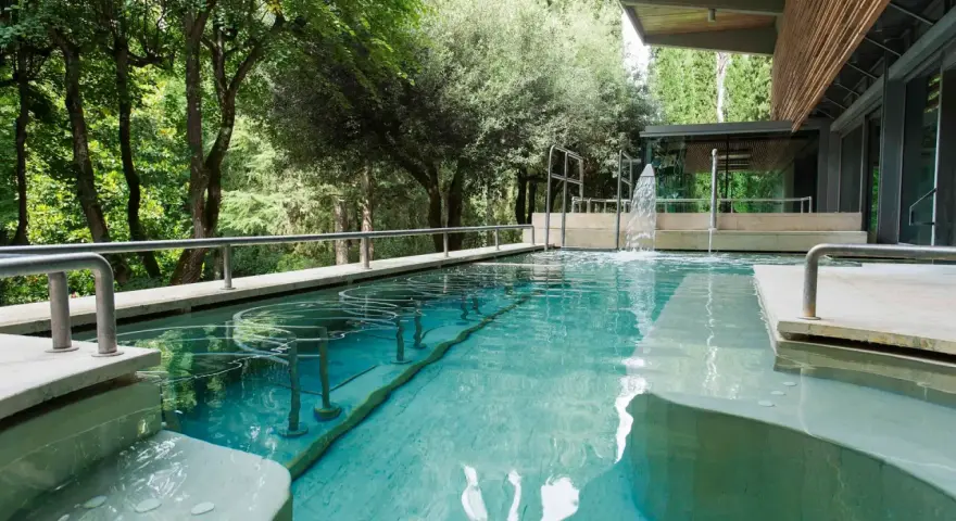 Piscina termale con cascata e alberi circostanti: un'oasi di relax da scoprire tra le cose da vedere a Chianciano Terme.