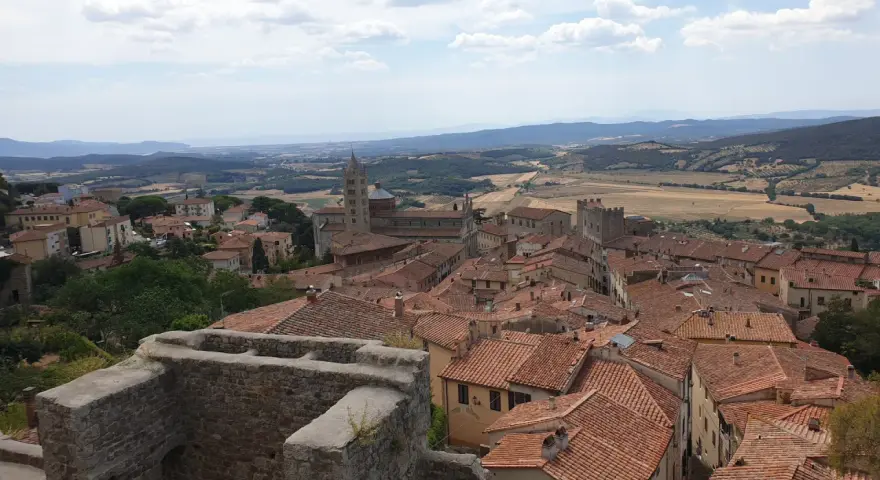 Panoramica di Massa Marittima con tetti rossi, una cattedrale imponente e colline toscane sullo sfondo.
