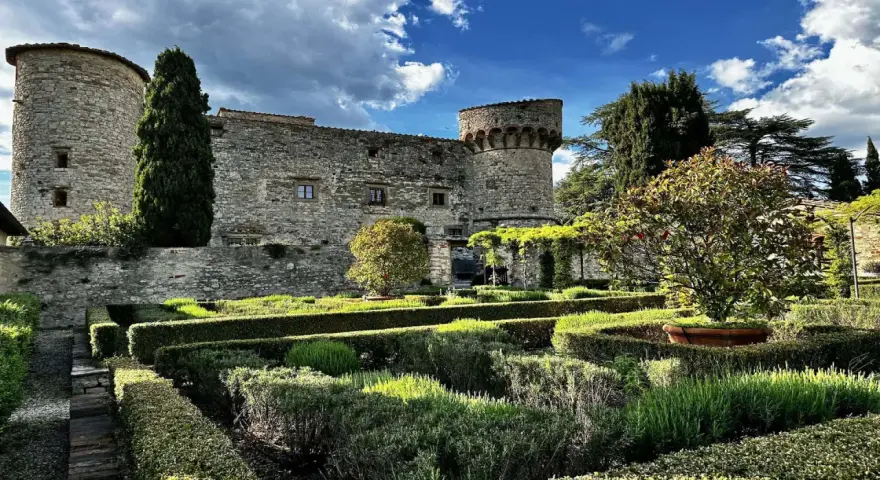 Giardini curati e torri antiche del castello di Meleto, un luogo ideale per visite indimenticabili.