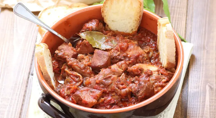 La scottiglia, un saporito stufato di carne in umido, servita in una ciotola di terracotta con fette di pane croccante.