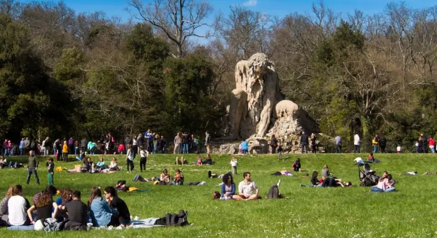 Pratolino: cosa vedere? La statua del Colosso dell'Appennino domina un prato verde affollato di persone che si godono il sole.