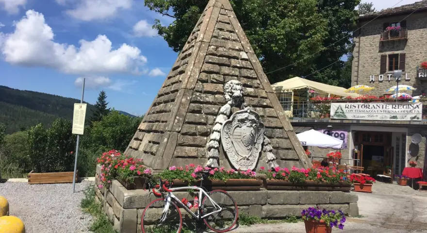 Le piramidi di Abetone, con una bici da corsa appoggiata, circondate da fiori e un ristorante.