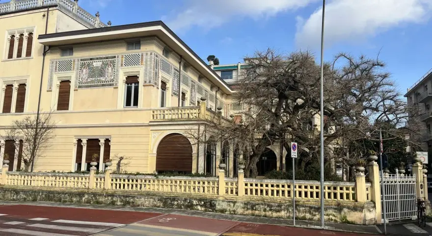 Villa Argentina a Viareggio, con la sua facciata decorata e un grande albero spoglio.