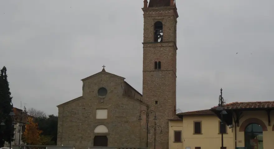 La chiesa di Sant'Agostino ad Arezzo, con il suo imponente campanile in pietra, si staglia contro un cielo nuvoloso.
