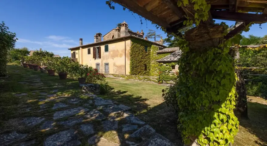Un casale toscano immerso nel verde, con un pergolato ricoperto d'edera. Un luogo ideale per gustare un buon dionisio vino.