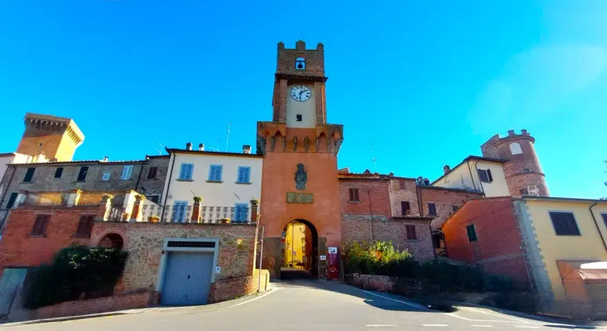 Torre dell'orologio a Marciano Italia, con un arco medievale e case in pietra.