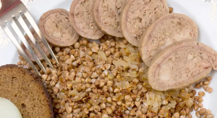 Piatto con grano saraceno, pane nero, cipolle e fette di collo ripieno.
