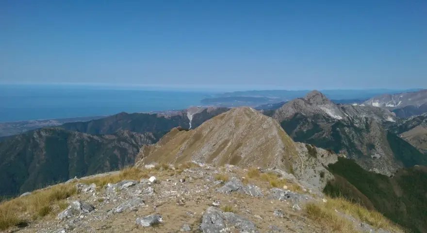 Panoramica mozzafiato dal monte Argegna, con il mare azzurro all'orizzonte e le cime rocciose che si stagliano contro il cielo limpido.