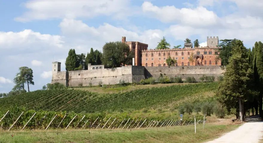 Il castello di Brolio domina le colline toscane, circondato da vigneti rigogliosi e cipressi secolari.