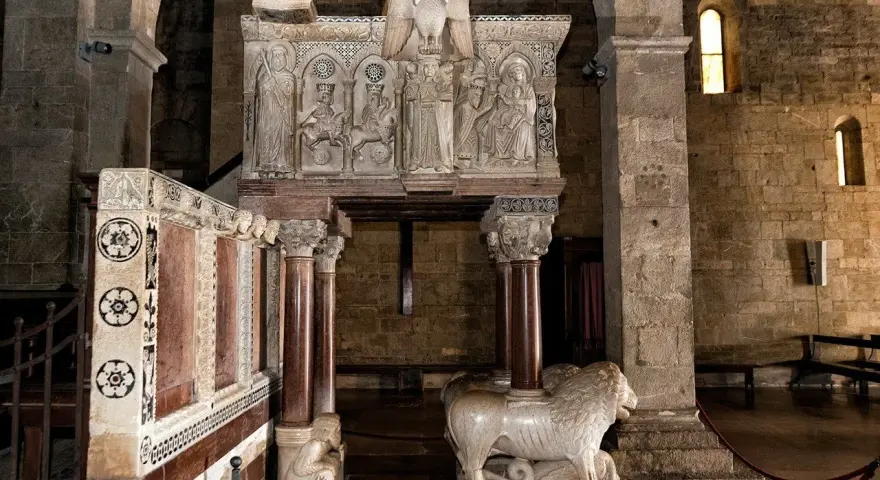 Interno del duomo di Barga con un leone in marmo e un pulpito scolpito.