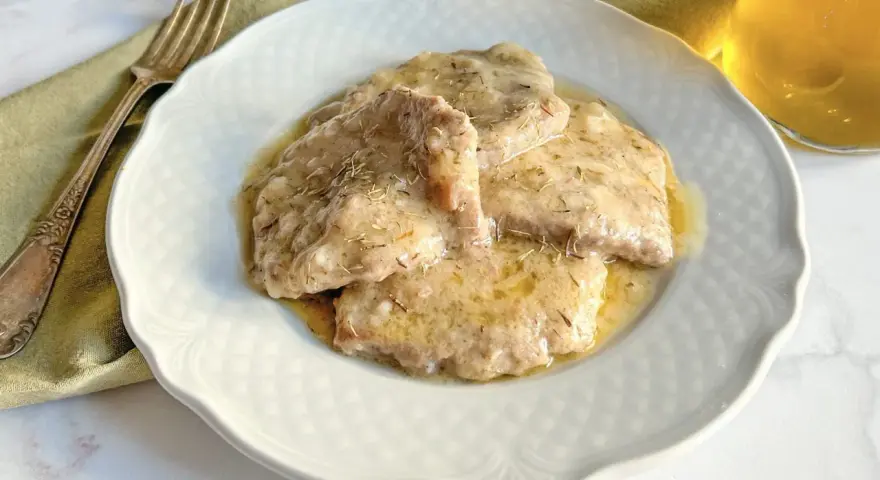 Grifi in umido, teneri e succulenti, serviti su un piatto bianco con forchetta e bicchiere di vino.