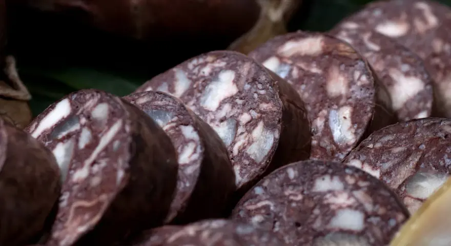Fette di biroldo toscano, un salume scuro con striature bianche, pronto per essere gustato.