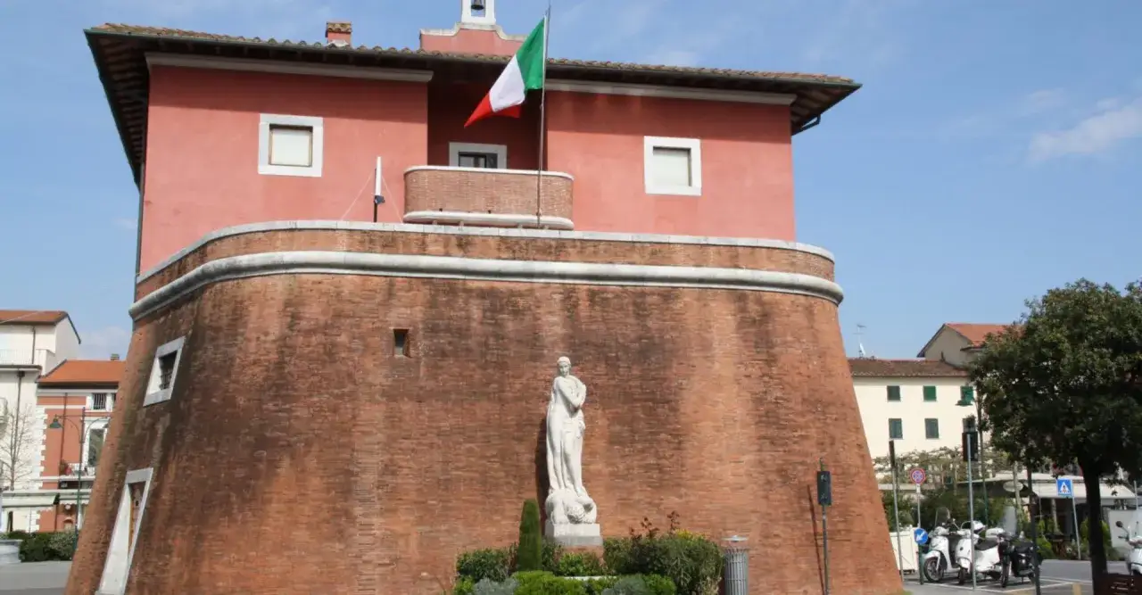 Il fortino Forte dei Marmi, con la bandiera italiana che sventola, domina la piazza con la sua imponente struttura in mattoni rossi e la statua bianca.