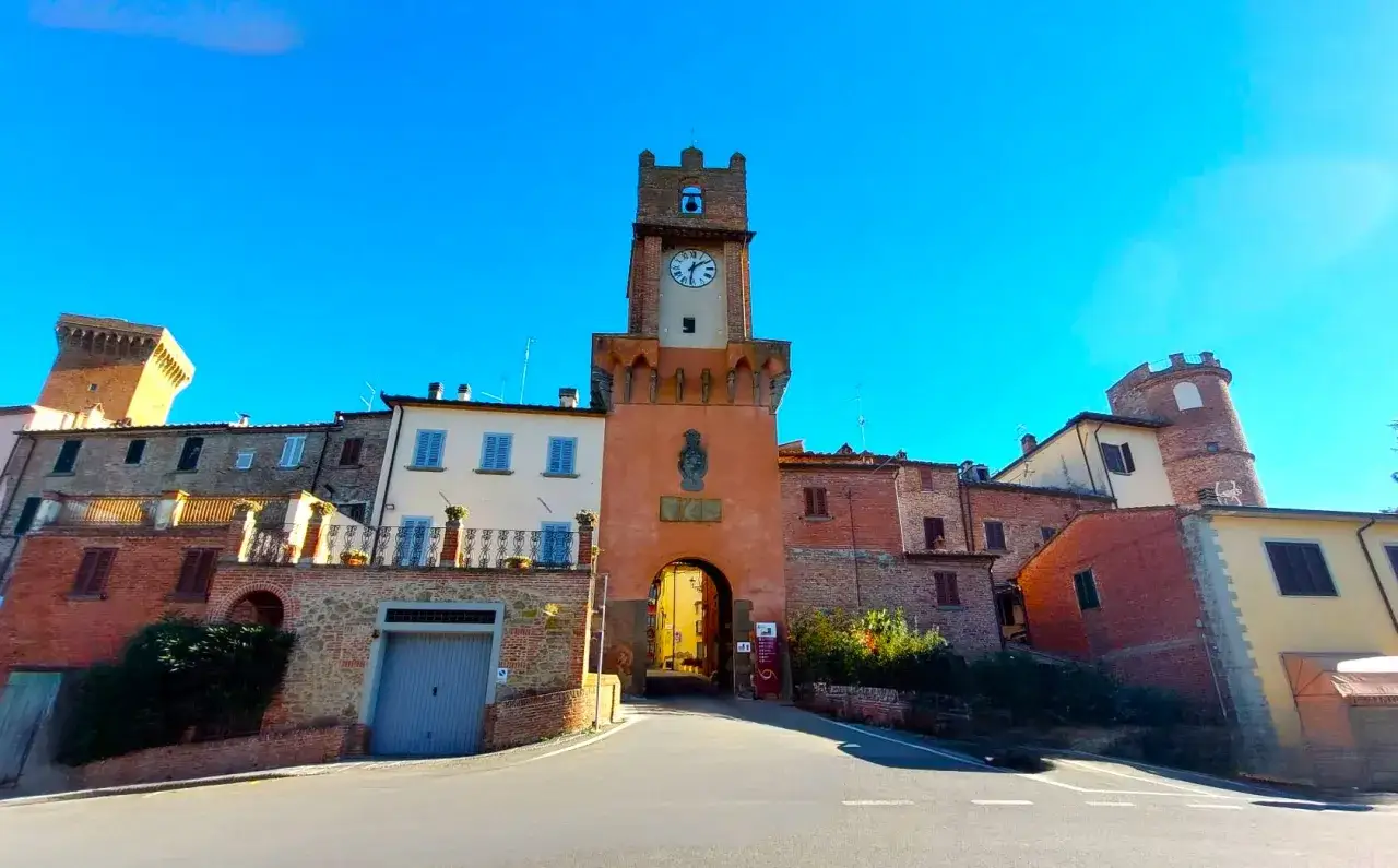 Torre dell'orologio medievale a Marciano Italia, con un arco che conduce a una strada acciottolata.